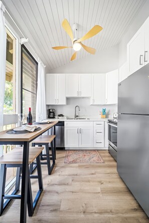 A modern kitchen with white cabinets, a stainless steel refrigerator, and a wooden dining table with benches.