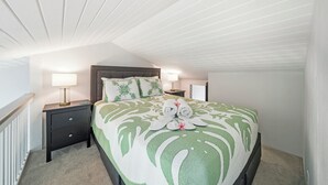 A bedroom with a bed, nightstands, lamps, and a ceiling with wooden beams. - Bright North Shore Condo With Loft, Golf Views, and Resort Amenities (Kahuku)