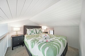 A bedroom with a bed, nightstands, lamps, and a ceiling with wooden beams. - Bright North Shore Condo With Loft, Golf Views, and Resort Amenities (Kahuku)