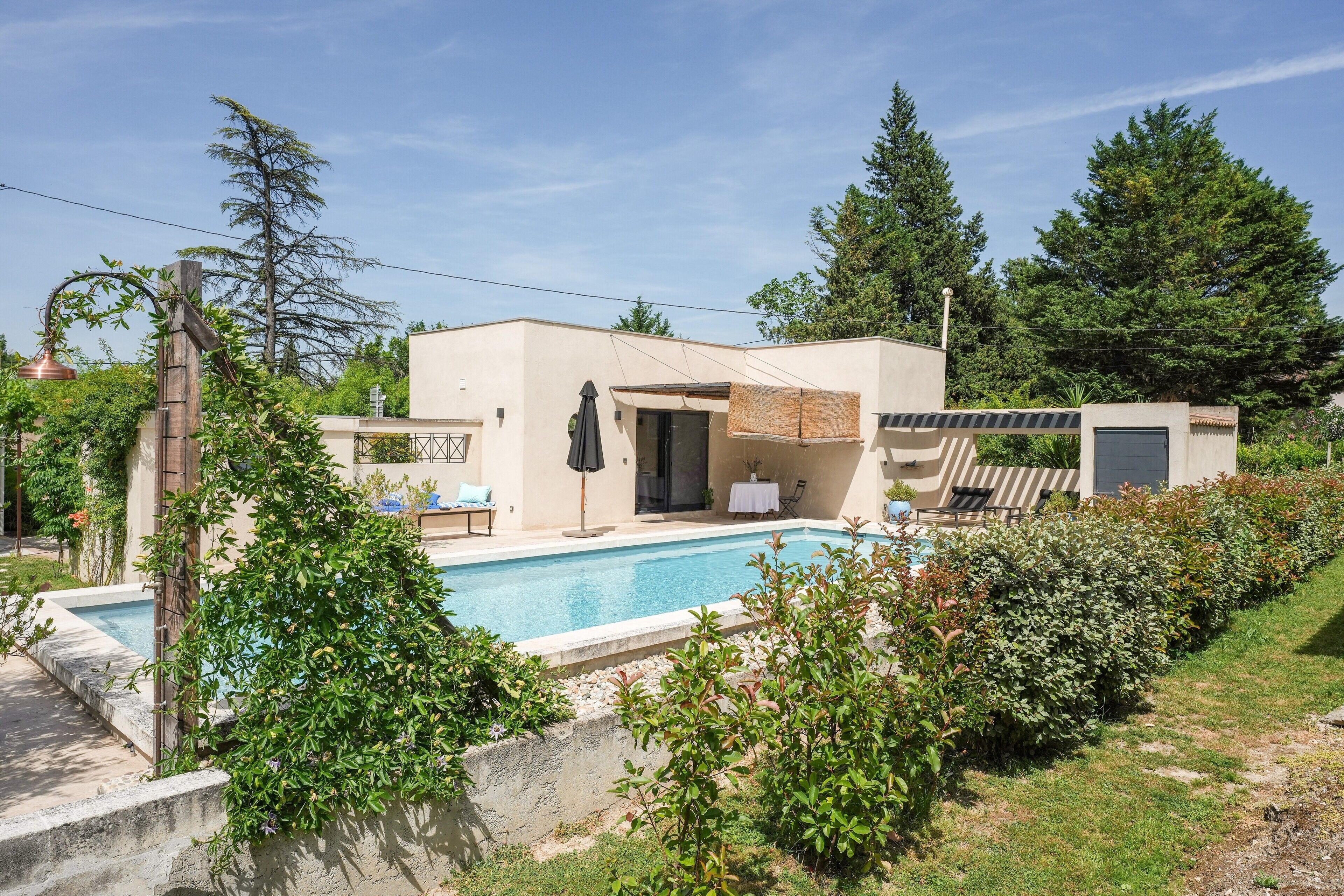 A modern house with a swimming pool, a patio with outdoor furniture, and a garage.