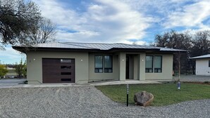 A modern single-story house with a garage, large windows, and a gravel driveway. - Fabulous 2-bedroom house with private boat ramp access to the Sacramento River (Redding)