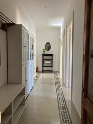 A hallway with a white cabinet, a mirror, and a patterned rug. - Apartment with panoramic view - Holiday Home Giulia (Roma)