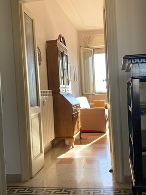 A hallway with a wooden cabinet, a white door, and a bed with a yellow pillow. - Apartment with panoramic view - Holiday Home Giulia (Roma)