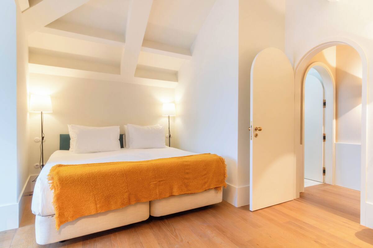 Une chambre à coucher avec un lit, deux lampes de chevet et une porte donnant sur une autre pièce.