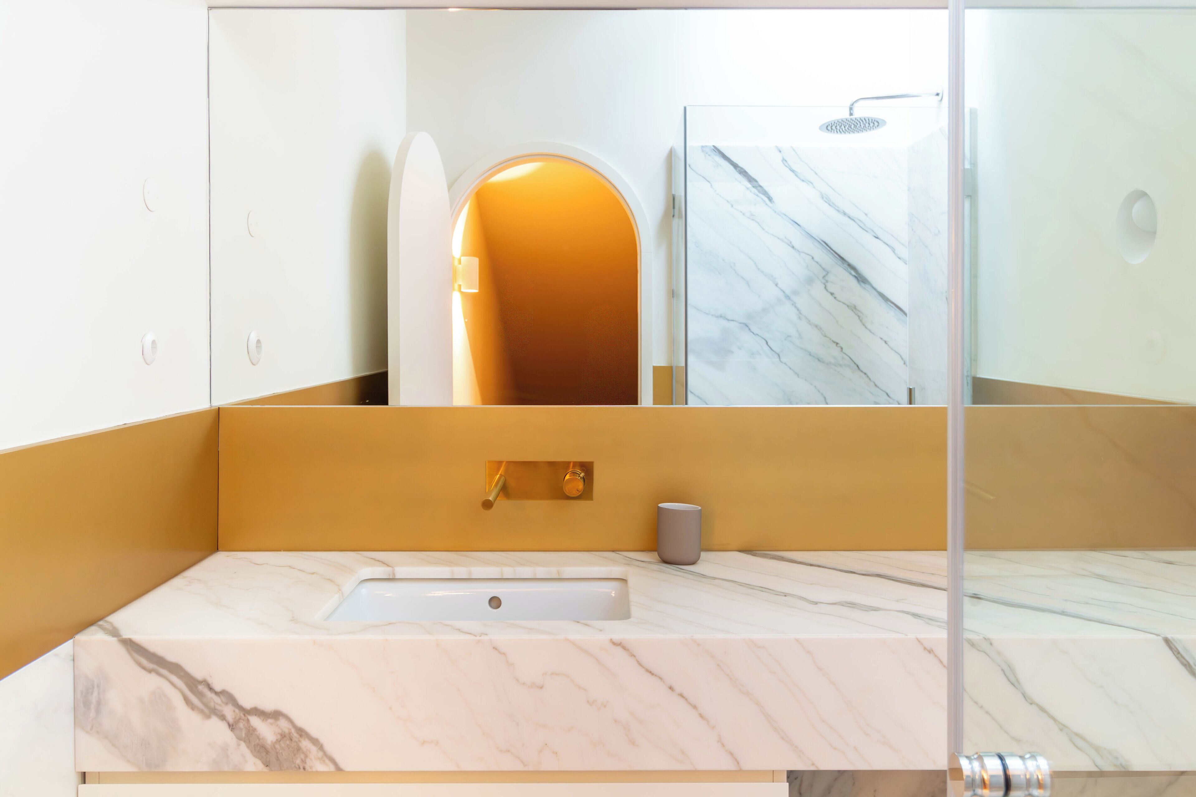 Un baño con lavamanos de mármol, espejo y zona de ducha.