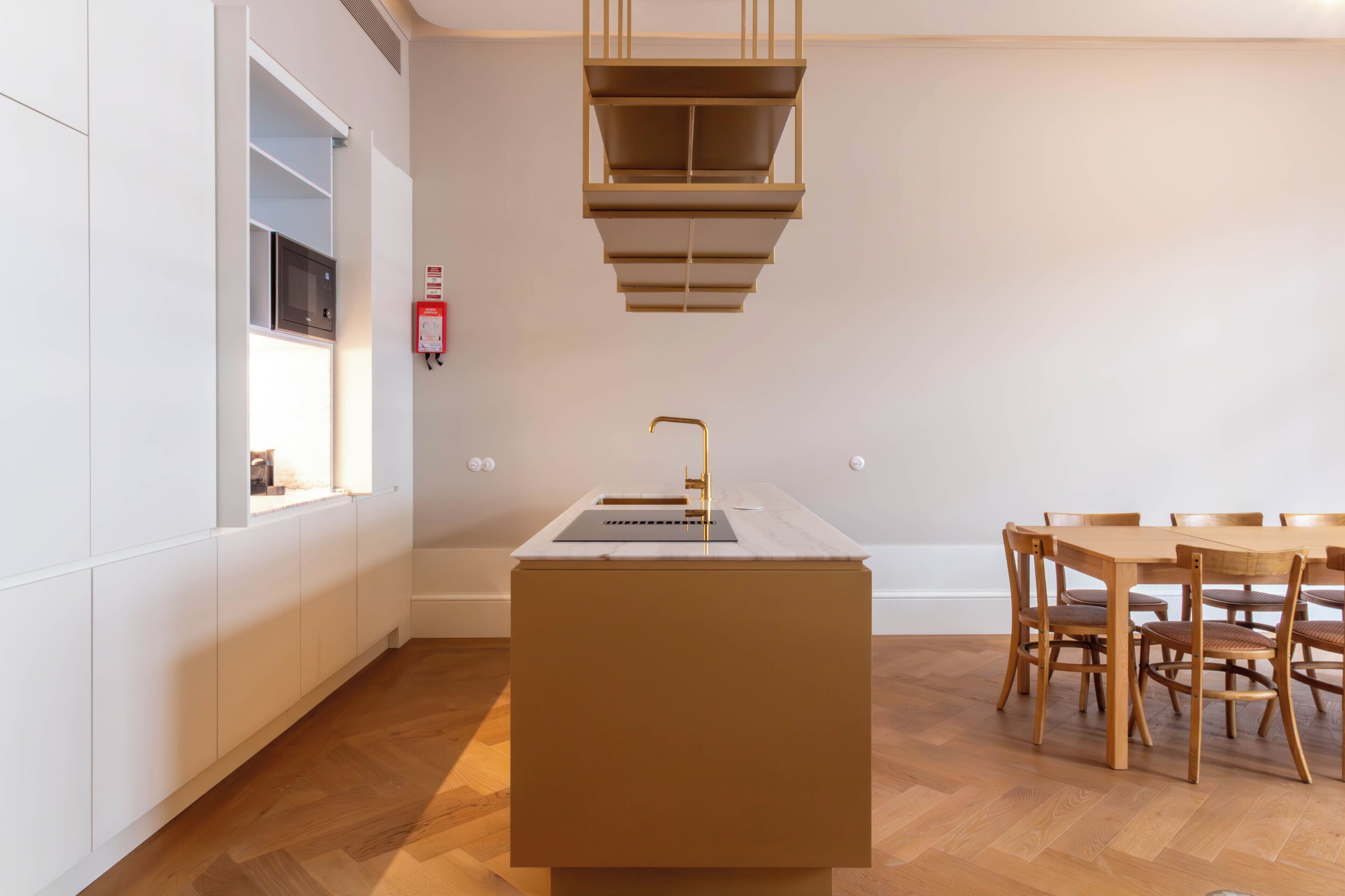 A modern kitchen with a central island, wooden dining table, and chairs.