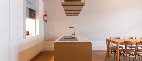 A modern kitchen with a central island, wooden dining table, and chairs.