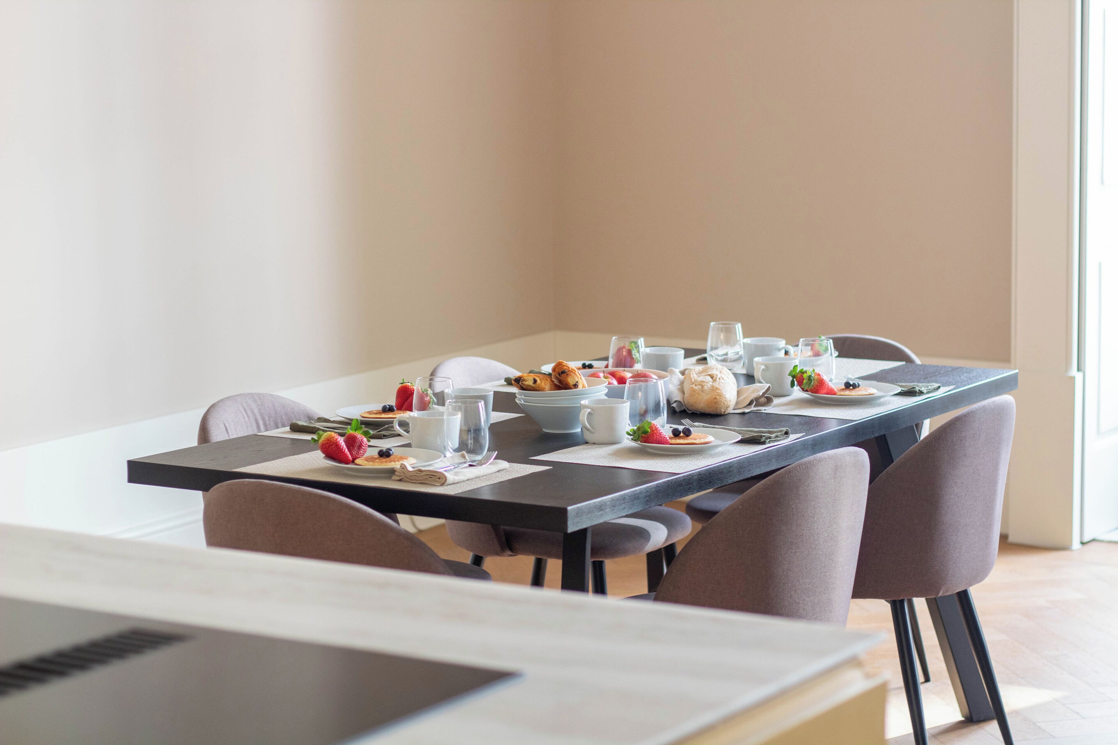 A dining table set with plates, glasses, and a laptop.