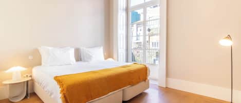 Une chambre à coucher avec un lit, une fenêtre, une table de chevet et une lampe sur pied.