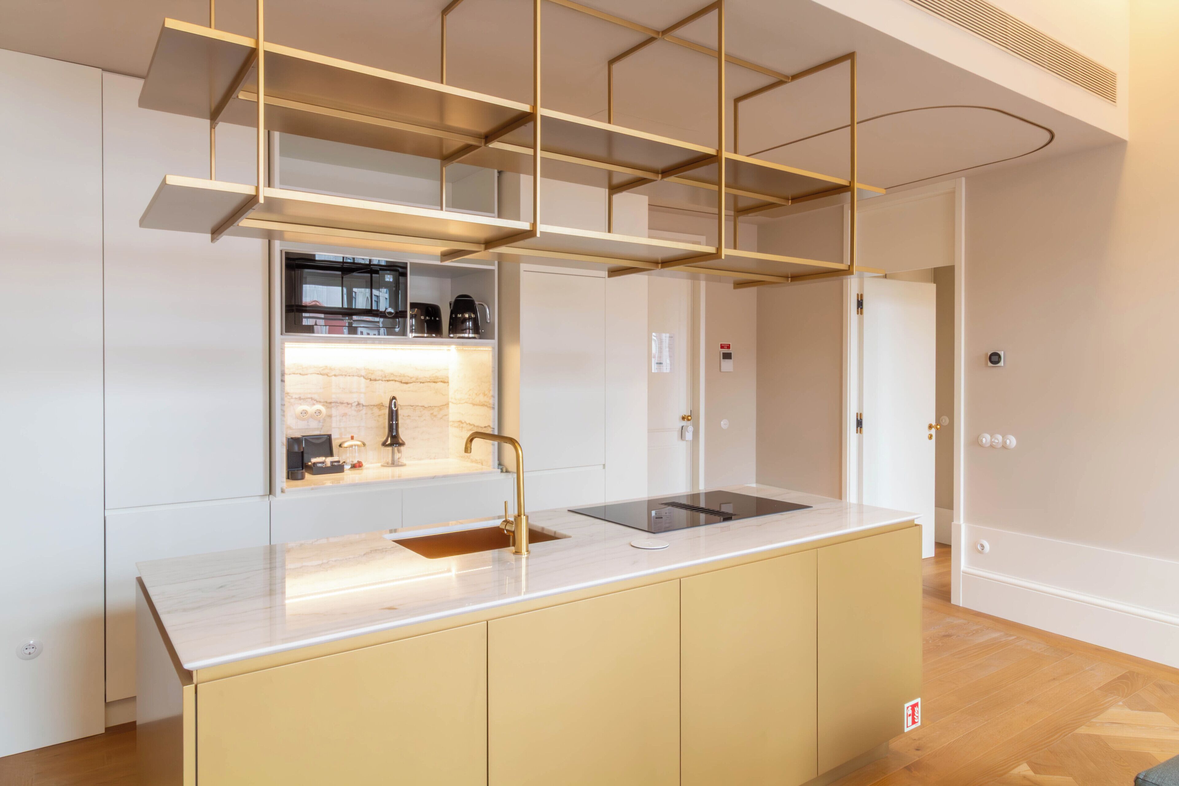 Una cocina moderna con una isla central, electrodomésticos integrados y una lámpara colgante.