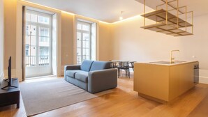 A modern living room with a sofa, a small island with a sink, and a dining area. - Entreparedes House (Porto)