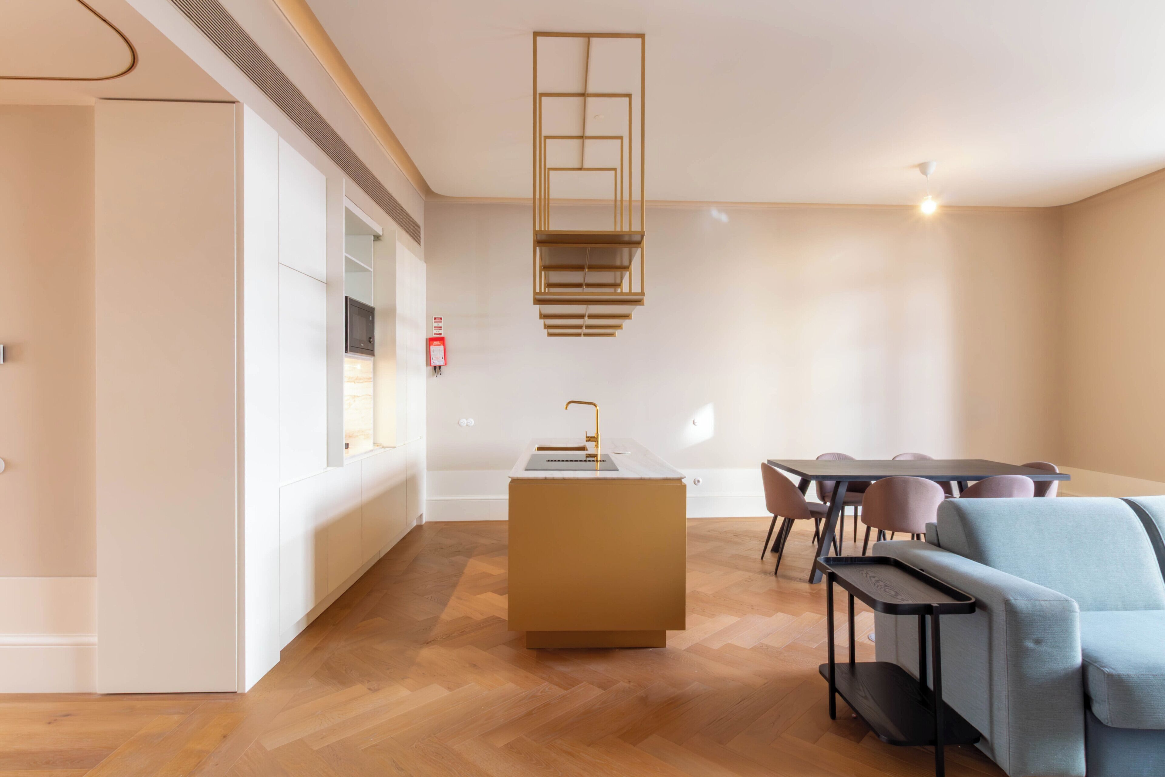A modern interior with a central island, wooden flooring, and a dining area with chairs and a table.