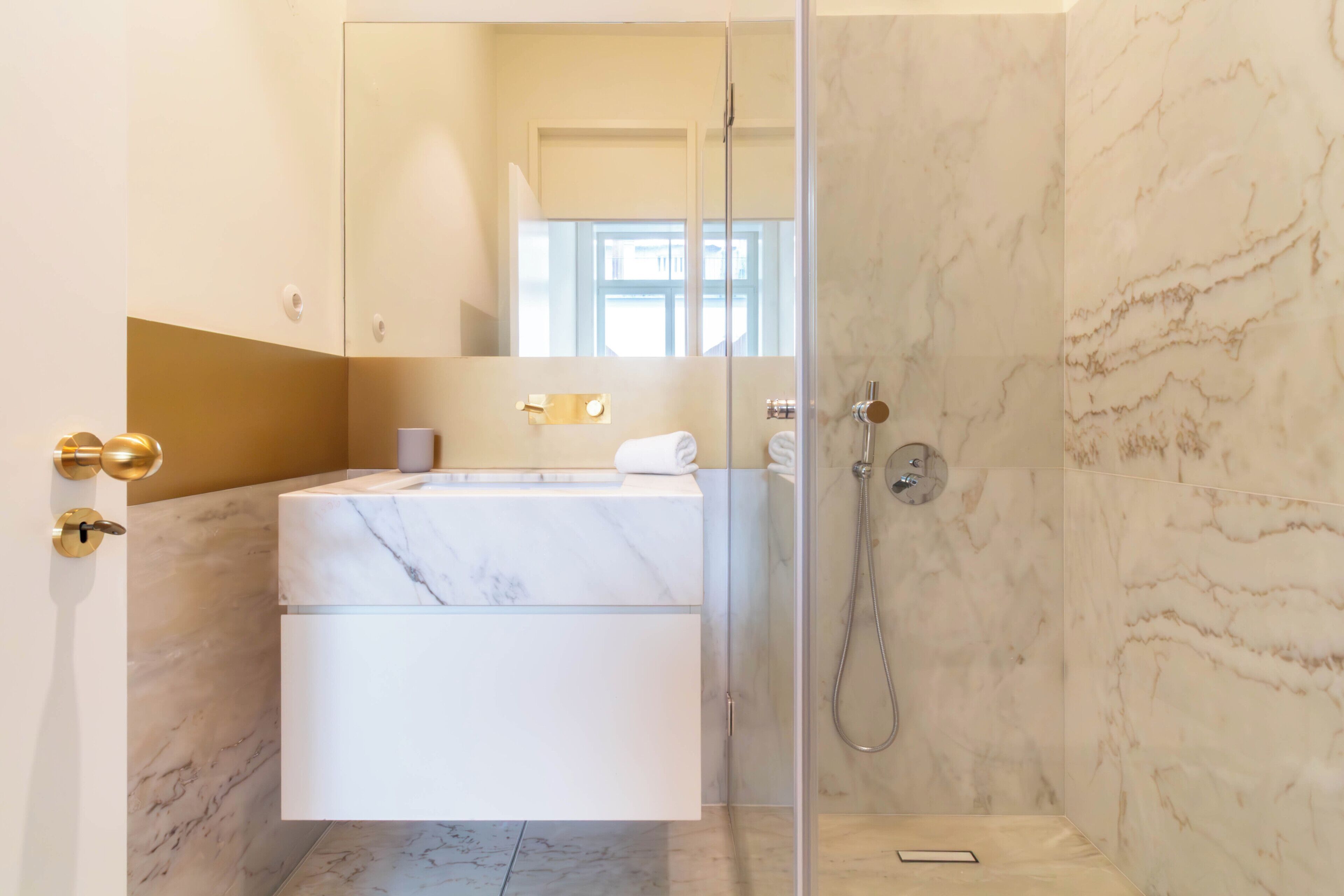 Une salle de bain moderne avec un lavabo en marbre, une douche en verre et un grand miroir.