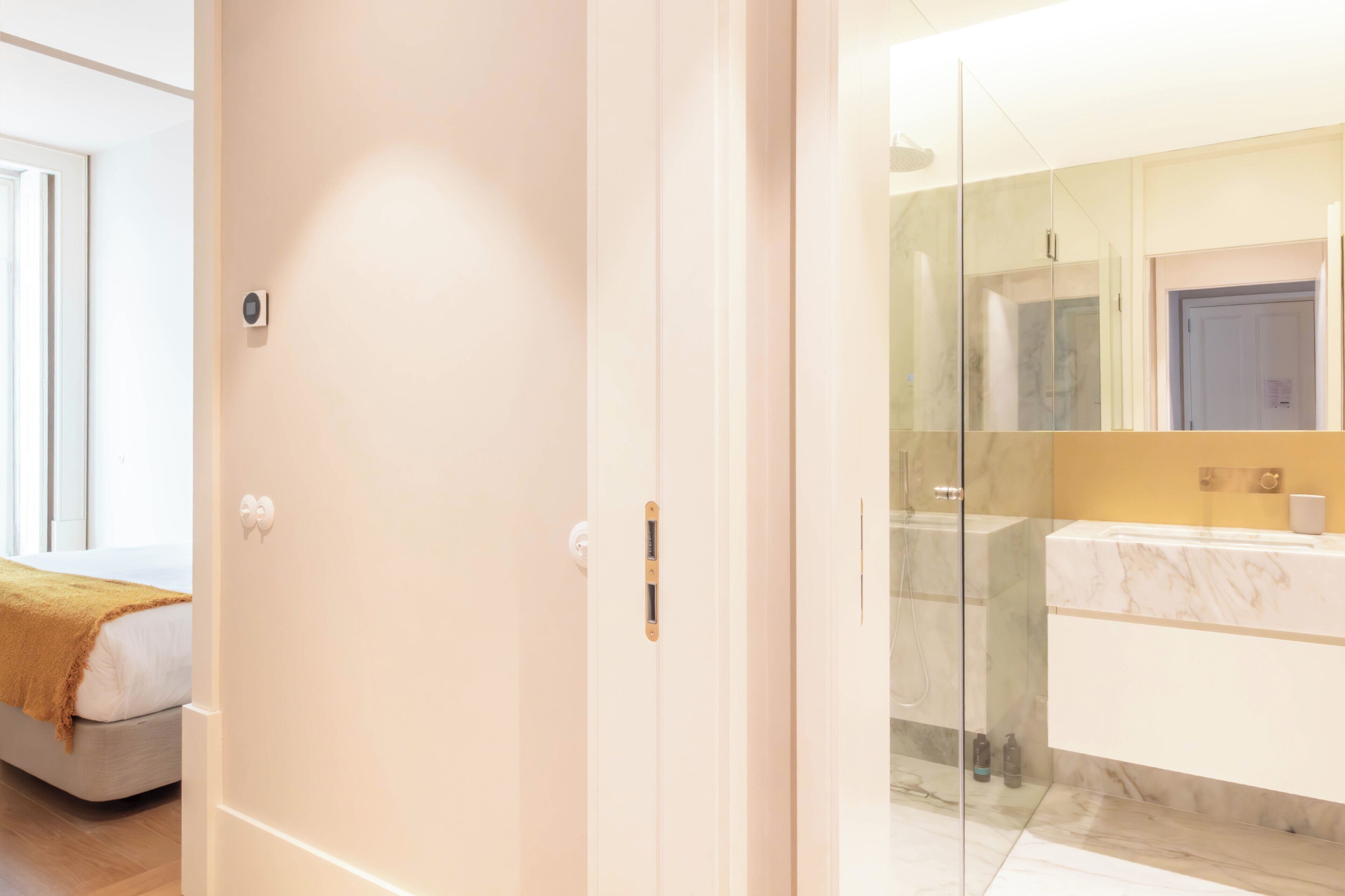 A modern bathroom with a glass shower enclosure, a marble countertop, and a large mirror.