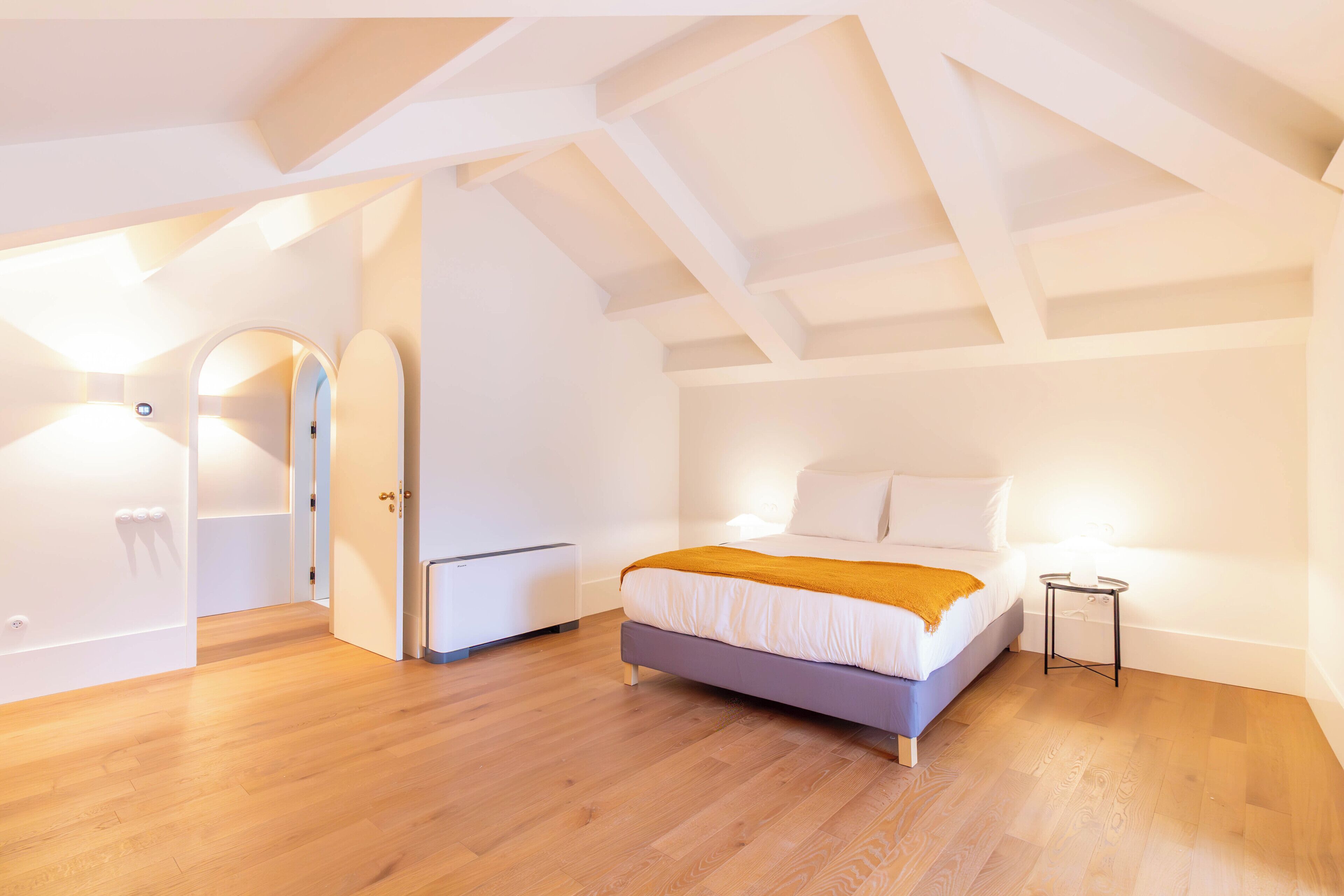 A modern bedroom with a bed, a small bedside table, and a wardrobe.