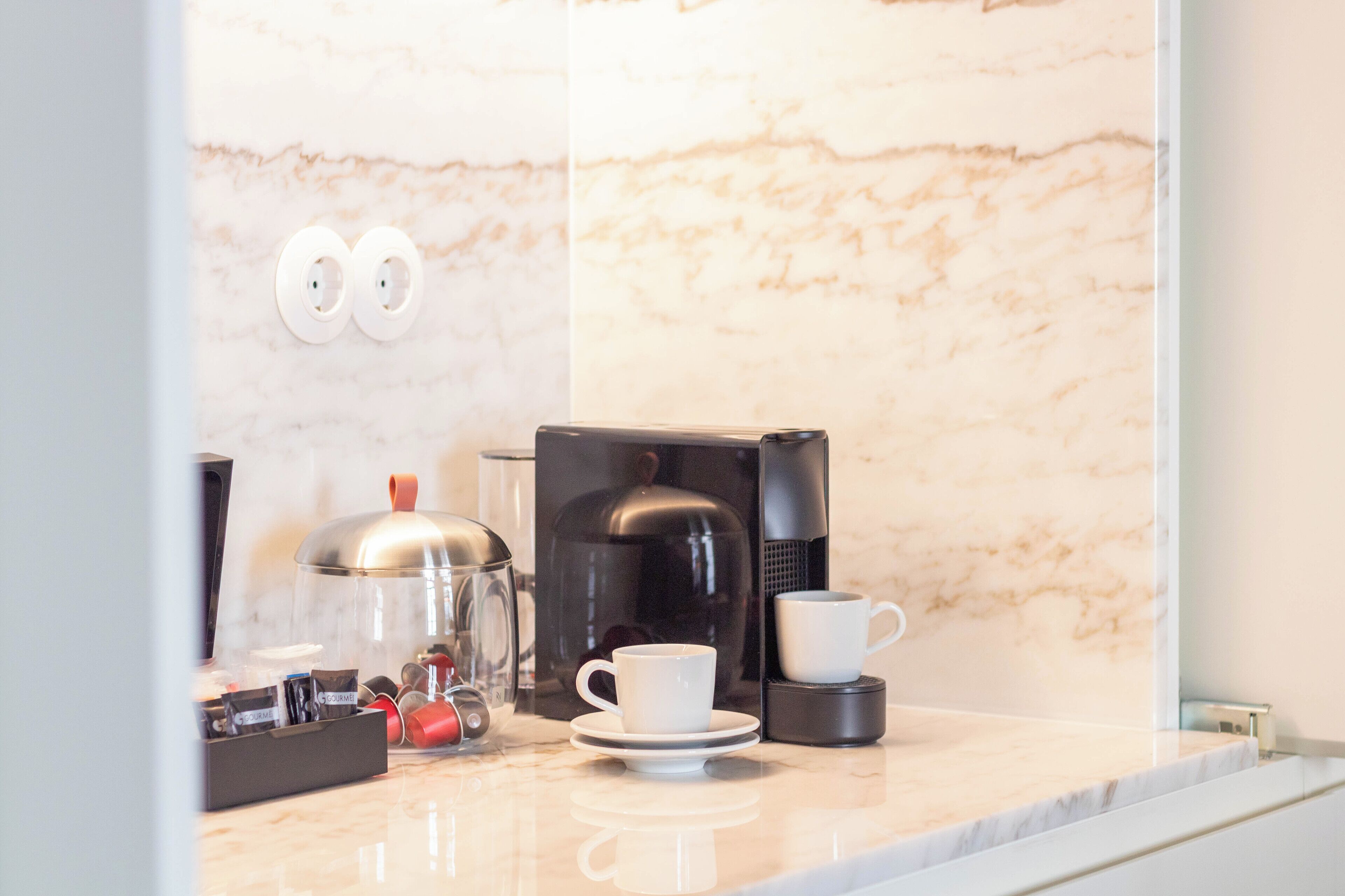 Eine moderne Küche mit Marmorarbeitsplatte, einer Kaffeemaschine, einer Tasse und einem Wasserkocher.