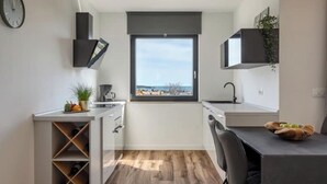 A modern kitchen with a view, built-in wine storage, and a dining area. - Apartment Citylight | Belvedere Holidays – Sea Views & Modern Comfort (Novigrad)