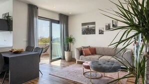 A modern living room with a sofa, ottoman, and dining area. - Apartment Citylight | Belvedere Holidays – Sea Views & Modern Comfort (Novigrad)