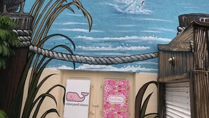 A mural of a pelican and a blue fish on a building with a sign for 'John's Pass Trading Company.' - The Cozy condo at Belleview Gulf (Indian Shores)