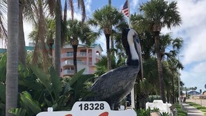 A sign for the Seaside Seabird Sanctuary with a large bird sculpture, surrounded by wooden posts and palm trees. - The Cozy condo at Belleview Gulf (Indian Shores)