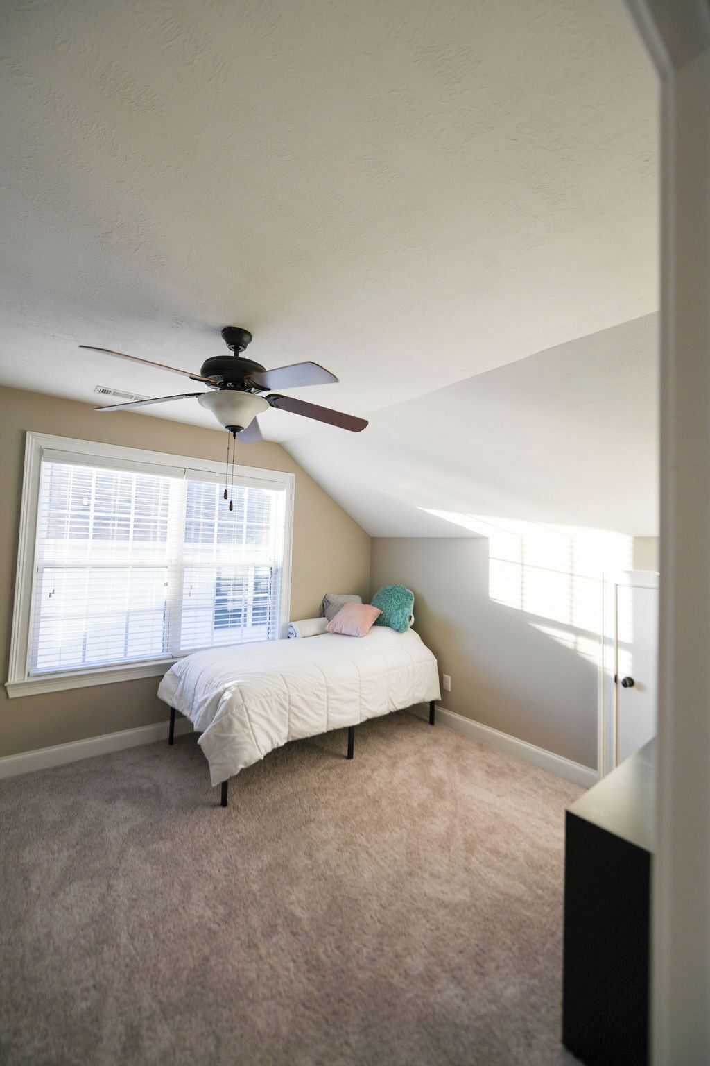 A bedroom with a bed, a ceiling fan, a window, and a door.