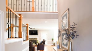 Un hall d’entrée spacieux, doté d’un plancher en bois, d’un banc, d’une cheminée et d’un escalier avec une rampe.
