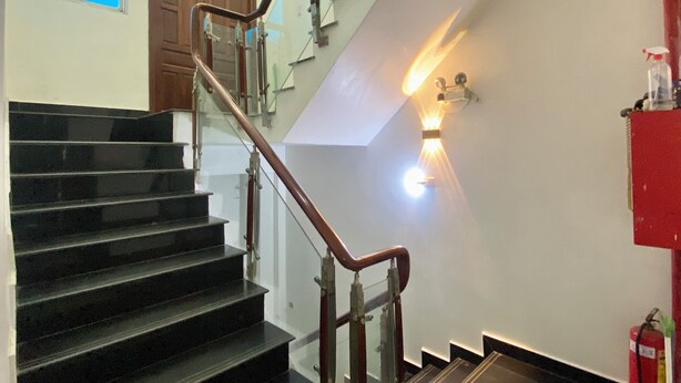 Un escalier doté d’une rampe en verre et d’un luminaire fixé au mur.