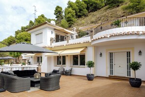 A spacious patio with outdoor furniture, a white building with a balcony, and a hillside backdrop. - Villa Estrella de la Montaña is much more than a holiday home (AN)