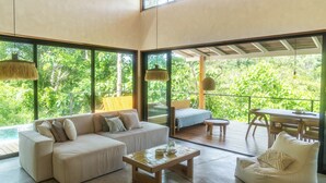Uma sala de estar ampla com sofá, mesa de centro e varanda com mesa e cadeiras.