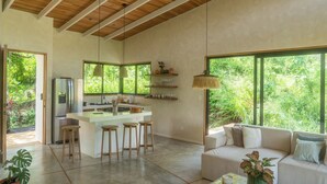 Cozinha espaçosa com ilha central, banquetas de bar e área de jantar com sofá.