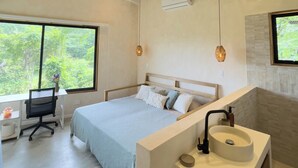 Quarto moderno com uma cama grande, uma escrivaninha e banheiro com pia e espelho.