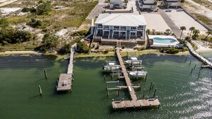 Une propriété située au bord de l’eau, dotée d’un quai, d’une piscine et d’un grand bâtiment comportant plusieurs terrasses.