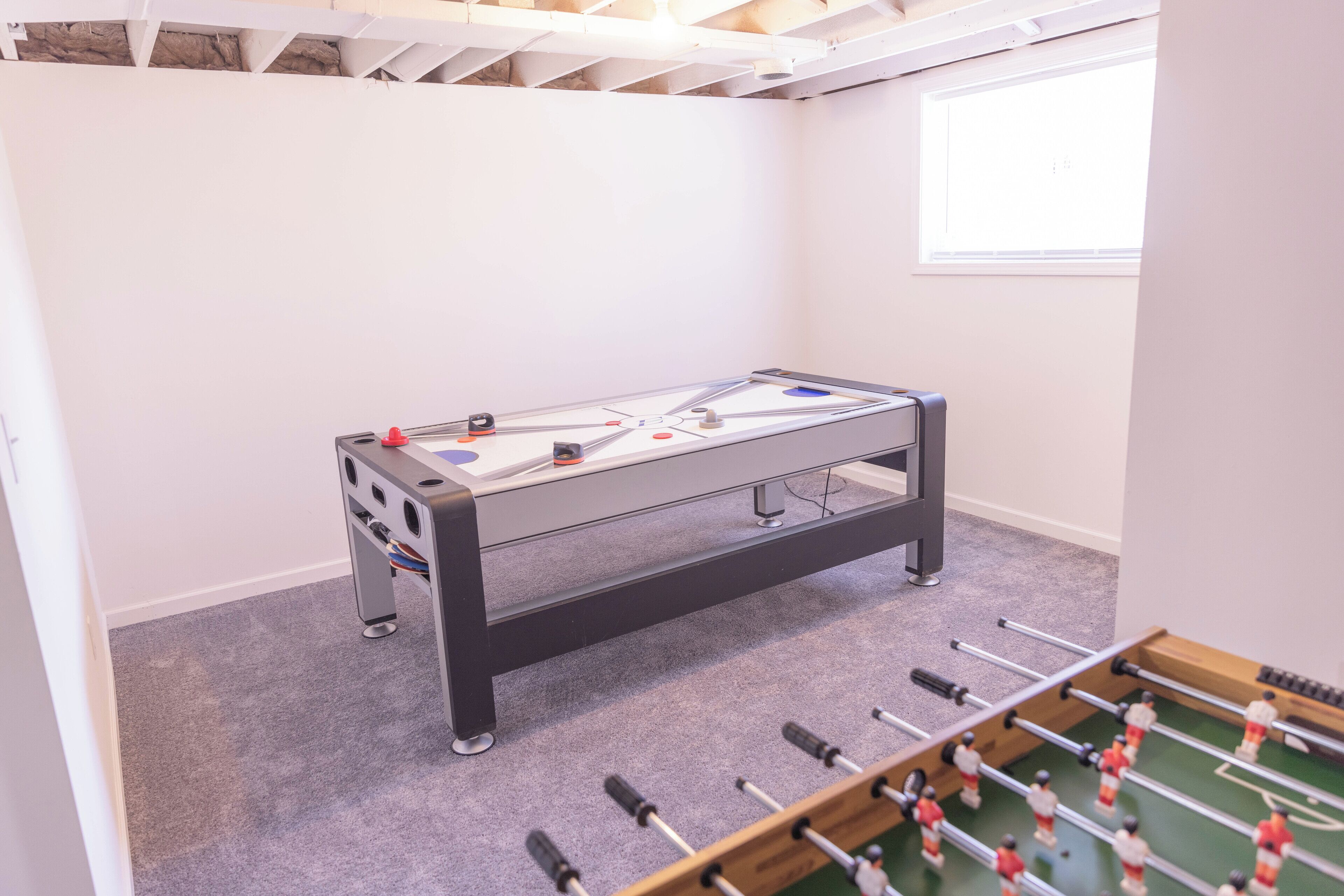 A room with a foosball table and a table tennis table.