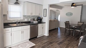 A modern kitchen with white cabinets, a built-in dishwasher, and a coffee station. - The Little Blue Inn (Rochester)