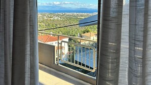 A balcony with a view of a coastal cityscape, including buildings and a body of water. - Aegean Hill Skyview (Rafina)