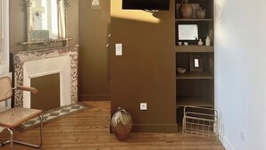 Una habitación con chimenea, espejo, televisor y piso de madera.