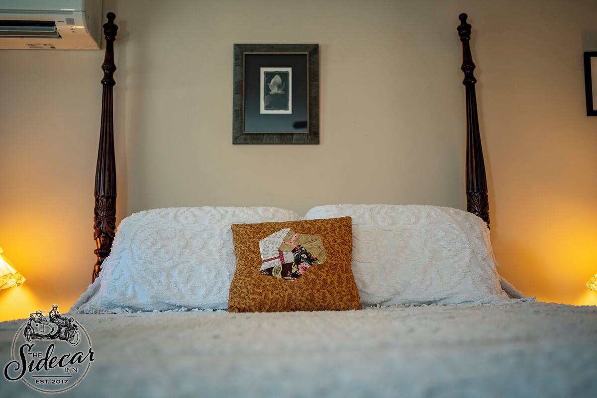 A neatly made bed with a decorative pillow and a framed picture on the wall.
