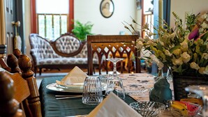 Une table à manger dressée avec des assiettes, des verres et des couverts, agrémentée d’un vase de fleurs et d’une bougie.