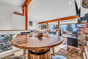 A spacious living area with a round wooden table, a stone fireplace, and a view of the outdoors. - Lakeview Incline Village Gem | Near Beach & Ski (Incline Village)