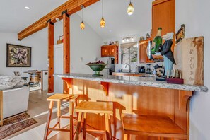 A modern kitchen with wooden accents, a bar area with stools, and a dining area with a white sofa. - Lakeview Incline Village Gem | Near Beach & Ski (Incline Village)