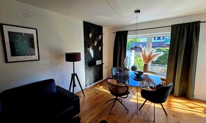 A room with a dining table, chairs, a black sofa, a floor lamp, and a wall with mounted deer skulls.