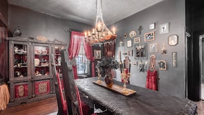 A dining area with a dark wooden table, red velvet chairs, and a chandelier.