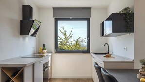 Et kompakt køkken med et vindue, indbyggede apparater og en vinhylde.