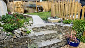 A stone staircase leading up to a wooden deck with a garden in the background. - Arcadia - 2-Bed, Dog Friendly with EV Charger (Mere)