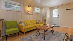 A living room with a yellow sofa, a green armchair, and a wooden coffee table. - Lower Unit  Killington Ski Stay w/ Fireplace & EV Charger (Killington)