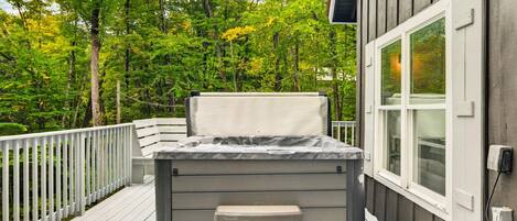 A hot tub on a wooden deck with a view of a forest.