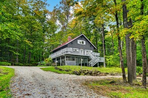 A cabin with a porch and stairs leading to a deck, surrounded by trees and a gravel path. - Powder Park | 4BR Killington Retreat w/ Private Hot Tub (Killington)