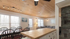A kitchen with a wooden island, white cabinets, and a stone fireplace. - Vermont Mountain Escape – Spacious Duplex with Privacy & Amenities (Killington)