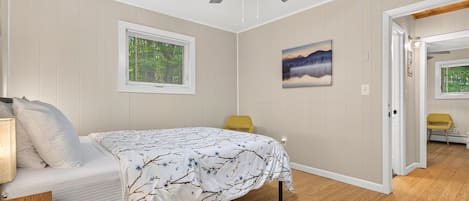 Drift off under the gentle breeze of the ceiling fan in this serene bedroom. Soft tones, natural light, and warm wood floors create your perfect retreat.