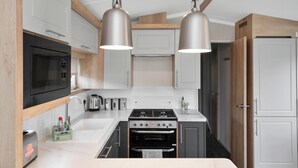 Eine moderne Küche mit weißen Schränken, einem Backofen, einem Gasherd und Pendelleuchten.